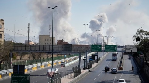 מכוניות נוסעות בכביש באיראן, כשברקע פטריות עשן